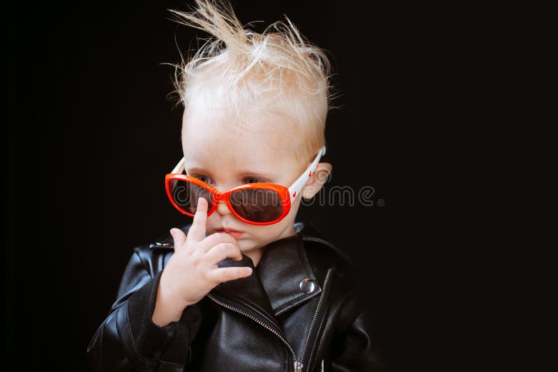 Piccolo ragazzo del bambino in rivestimento ed occhiali da sole dell'attuatore Bambino di stile della roccia immagine stock libera da diritti Piccolo ragazzo del bambino in rivestimento ed occhiali da sole dell'attuatore Bambino di stile della roccia immagine stock libera da diritti