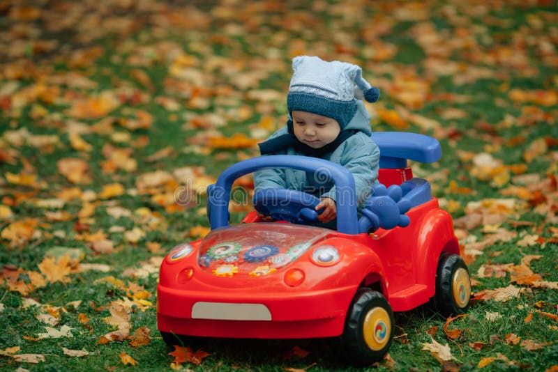 Piccolo ragazzo divertente che conduce l'automobile del giocattolo immagine stock libera da diritti Piccolo ragazzo divertente che conduce l'automobile del giocattolo immagine stock libera da diritti
