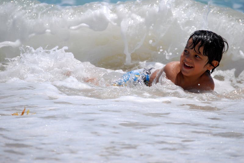 Piccolo ragazzo ispanico che gioca nelle onde di oceano immagini stock libere da diritti