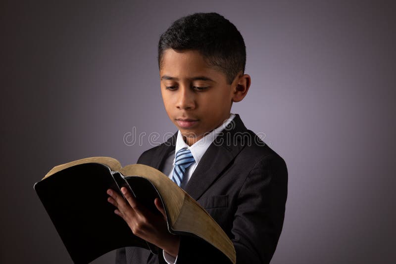 Piccolo ragazzo ispano che legge le sacre scritture sante, la bibbia, la parola di Dio immagini stock
