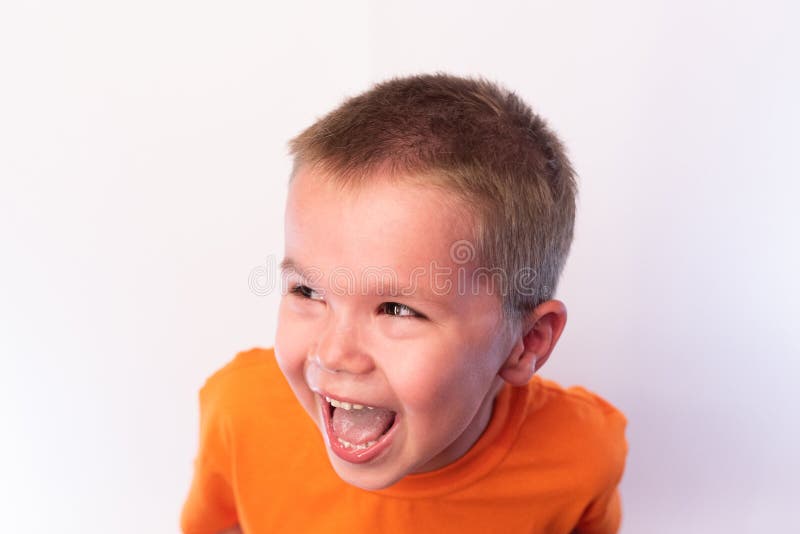 Piccolo ragazzo sveglio in una maglietta luminosa, ridente allegro contro un fondo luminoso fotografia stock Piccolo ragazzo sveglio in una maglietta luminosa, ridente allegro contro un fondo luminoso fotografia stock