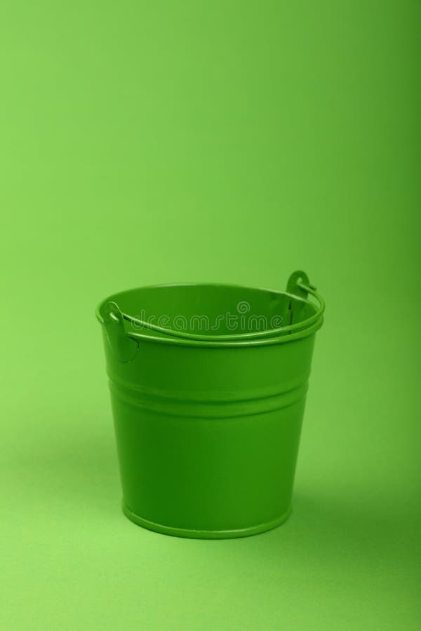 Piccolo secchio del metallo sulla fine verde del fondo su immagine stock libera da diritti Piccolo secchio del metallo sulla fine verde del fondo su immagine stock libera da diritti