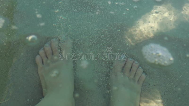 Picioare femele sub apă jucându-se cu nisip. Femeia înoată în mare în vacanță. Esența relaxării și a evadării tropicale stock video footage