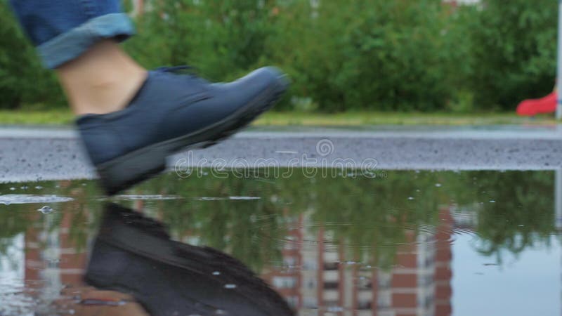 Picioarele femelelor în ghete merg în băltoacă stock footage