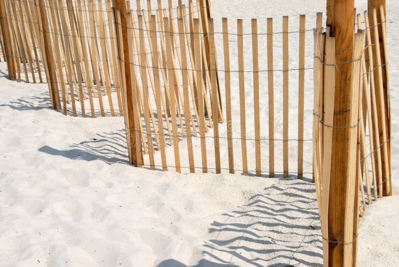 Picket fence on white sand beach.