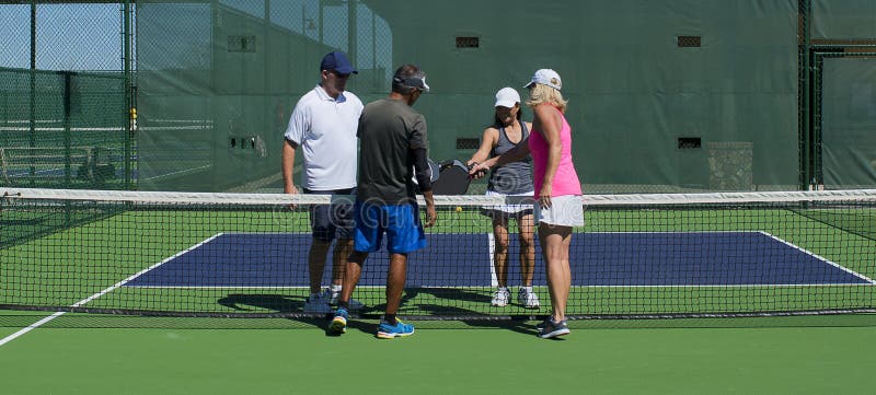 Colorful image of mixed double pickleball players immediately following a g...