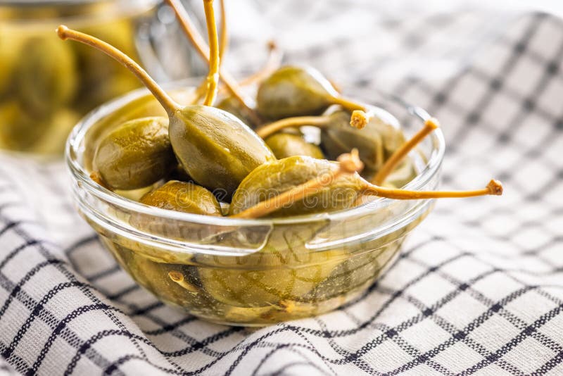 Pickled capers berries in bowl on checkered napkin stock photos