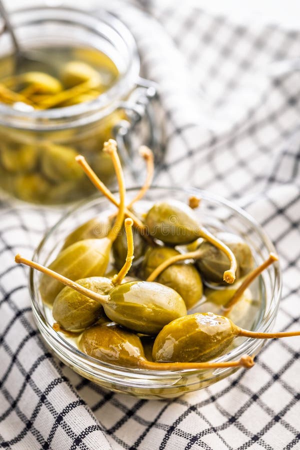Pickled capers berries in bowl on checkered napkin stock images