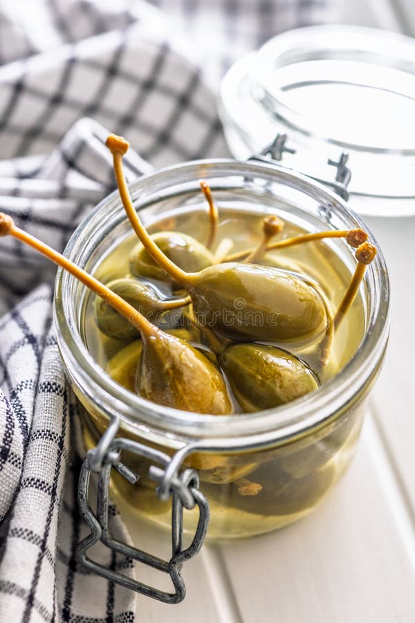 Pickled capers berries in bowl on white table stock images