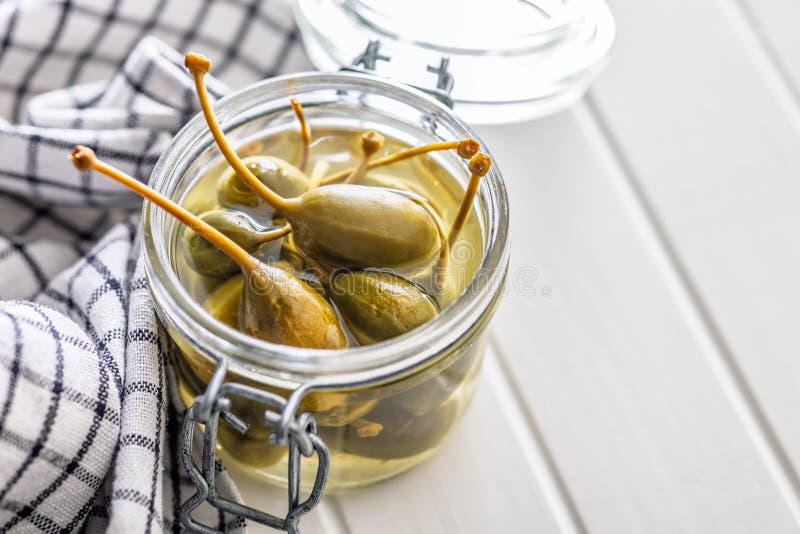 Pickled capers berries in bowl on white table royalty free stock photo