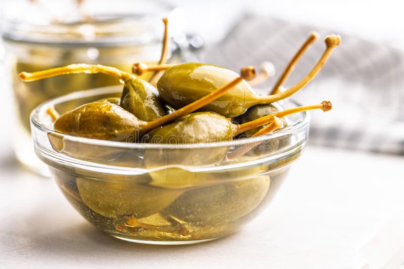 Pickled capers berries in bowl on white table royalty free stock image