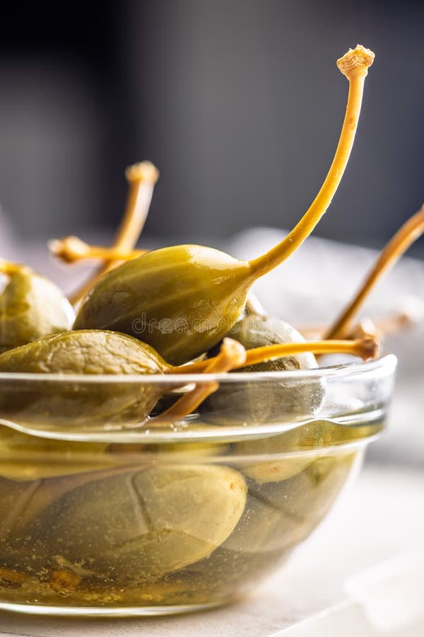 Pickled capers berries in bowl on white table royalty free stock photos
