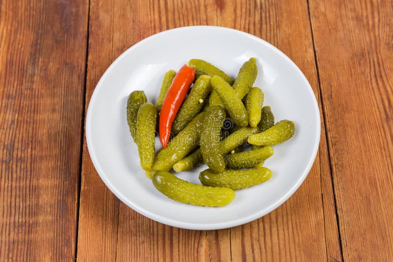 Pickled Gherkins on White Saucer on the Rustic Table Stock Photo