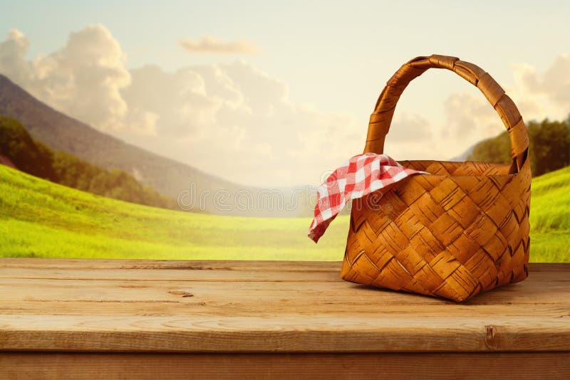 Picnic basket with checked tablecloth on wooden table