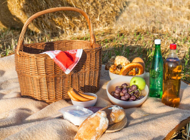 Picnic Basket And Different Food And Drinks On Straw Field Stock Photo