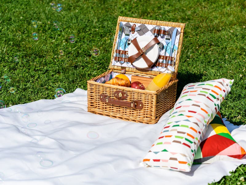 Picnic Basket on White Blanket with Pillows and Soap Bubbles Stock