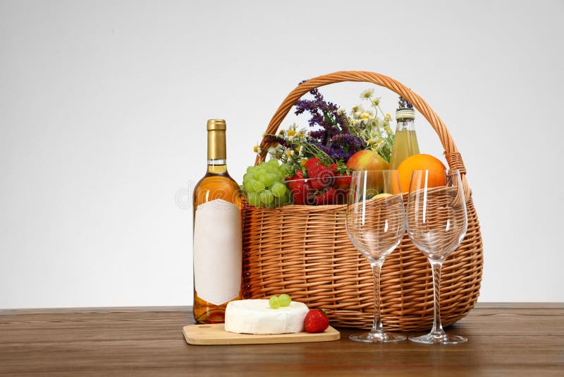 Picnic basket with wine and products on wooden table against white background