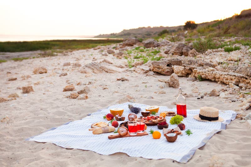 Picnic on the beach at sunset in the white plaid, food and drink royalty free stock photo Picnic on the beach at sunset in the white plaid, food and drink royalty free stock photo