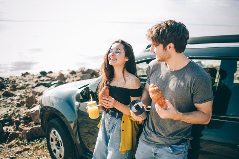 Picnic near the water. Happy family on a road trip in their car. Man and women are traveling by the sea or the ocean or the river. Summer ride by automobile. They stopped for a snack. Picnic near the water. Happy family on a road trip in their car. Man and women are traveling by the sea or the ocean or the river. Summer ride by automobile. They stopped for a snack