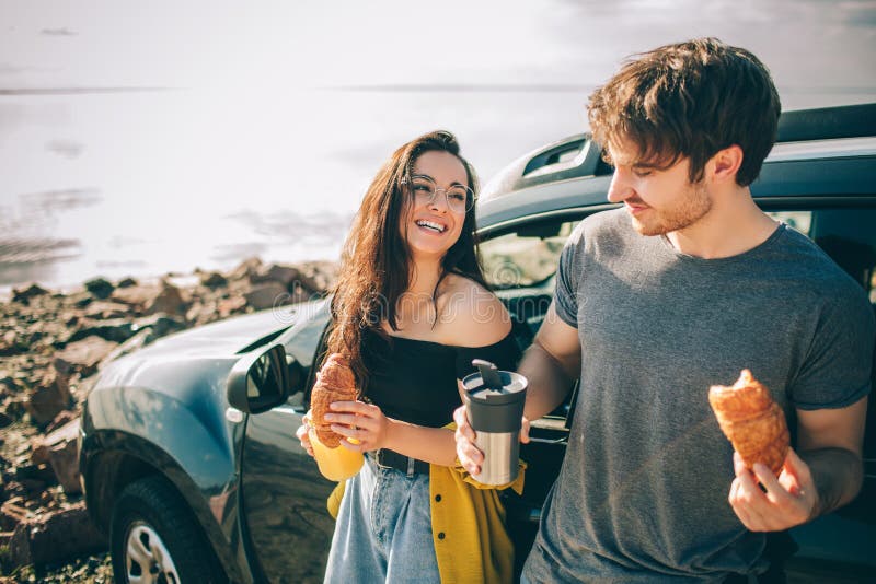 Picnic near the water. Happy family on a road trip in their car. Man and women are traveling by the sea or the ocean or the river. Summer ride by automobile. They stopped for a snack. Picnic near the water. Happy family on a road trip in their car. Man and women are traveling by the sea or the ocean or the river. Summer ride by automobile. They stopped for a snack