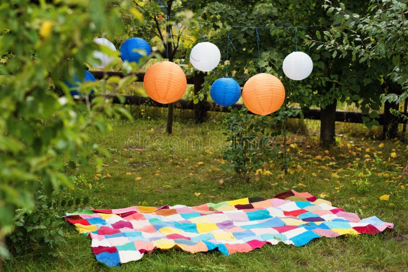 Picnic setting outdoors with plaid and paper lanterns. Celebration, party concept, romance, love date theme.