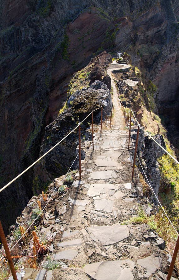 A narrow passage along a ridge with high cliffs both sides. Pico do Areeiro to Pico Ruivo hiking trail, Madeira, Portugal. A narrow passage along a ridge with high cliffs both sides. Pico do Areeiro to Pico Ruivo hiking trail, Madeira, Portugal.