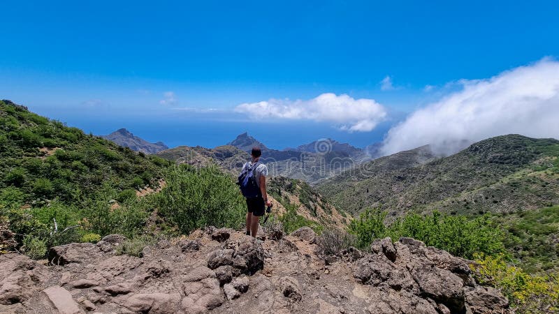 Pico verde man med ryggsäck med panoramisk syn på teno-bergsmassivet från toppmötet pico verde tenerife. arkivfoton
