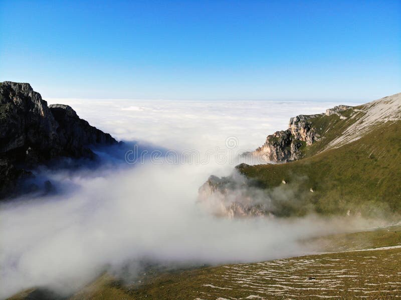 Picos de montanha do Cáucaso que eleva-se acima das nuvens Névoa no desfiladeiro da montanha imagem de stock Picos de montanha do Cáucaso que eleva-se acima das nuvens Névoa no desfiladeiro da montanha imagem de stock