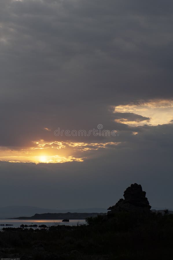 Picos de um nascer do sol da manhã através das nuvens pesadas para revelar uma silhueta de um tufo no mono lago fotografia de stock royalty free Picos de um nascer do sol da manhã através das nuvens pesadas para revelar uma silhueta de um tufo no mono lago fotografia de stock royalty free