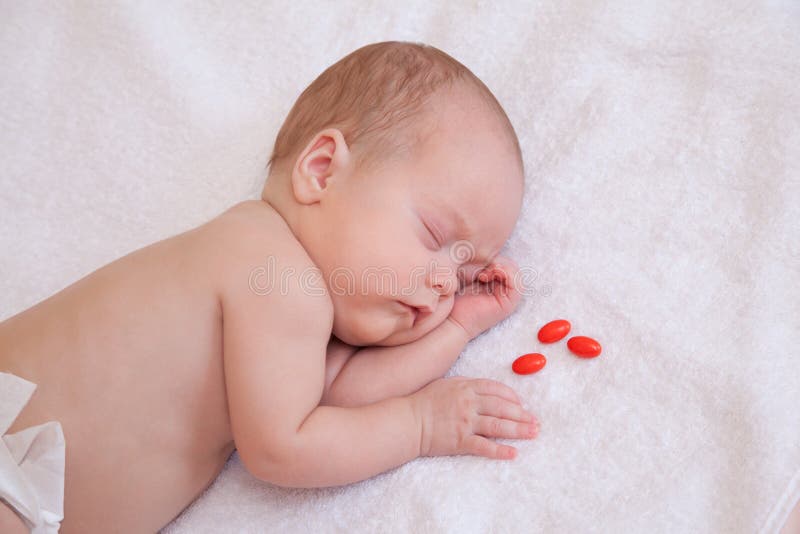 Picture of baby sleeping on the blanket with three pills