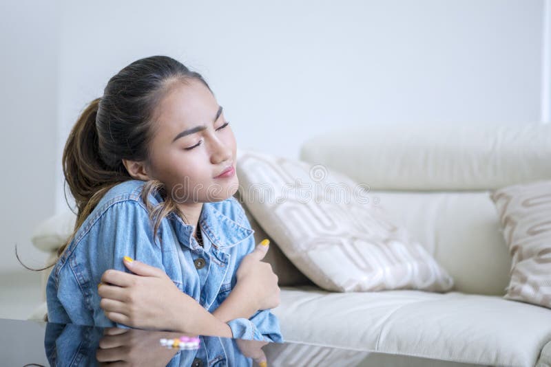 Picture of drugs addict girl sitting in the living room while shivering with drugs on the table at home. Picture of drugs addict girl sitting in the living room while shivering with drugs on the table at home