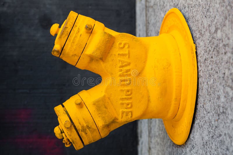 Old yellow standpipe at a building in New York City, USA