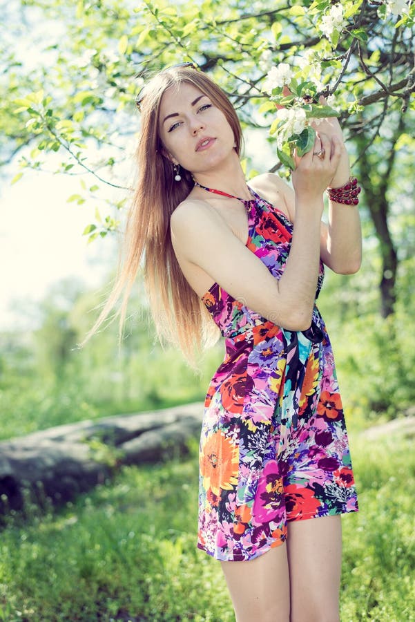 Picture of spring time & beautiful blonde young lady pretty girl with blue eyes standing under blooming tree & looking at camera stock images Picture of spring time & beautiful blonde young lady pretty girl with blue eyes standing under blooming tree & looking at camera stock images