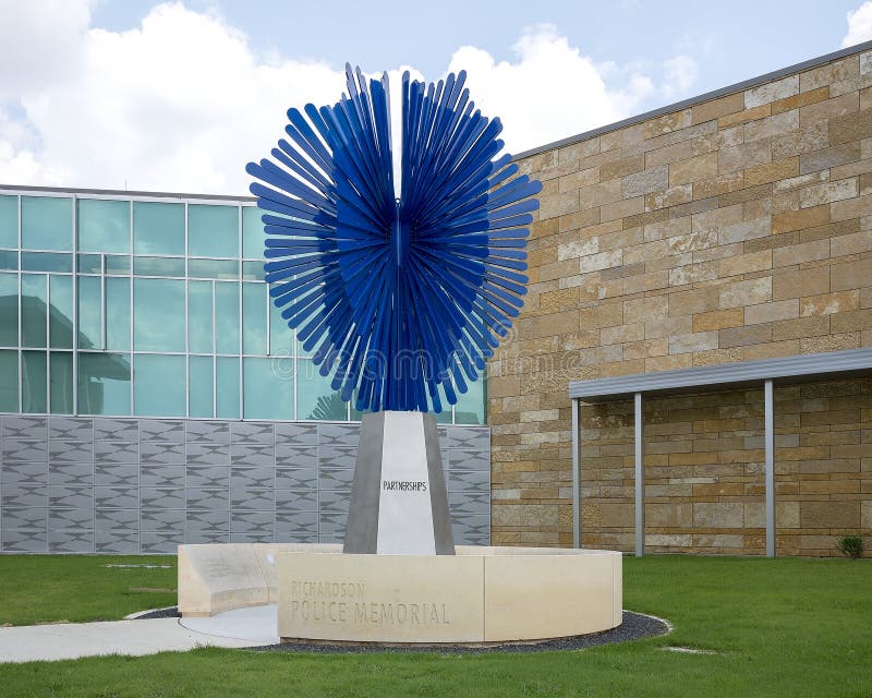 Pictured is a sculpture titled `Radiant Shield` by Shane Allbirtton and Norman Lee at the police station in the City of Richardson, Texas.  It is part of a police memorial, it`s surrounding low limestone wall being engraved on the inside with a quote, a poem, a reference to a fallen officer, and a dedication to the officers of the Richardson Police Department who have given their lives while serving and protecting the citizens.