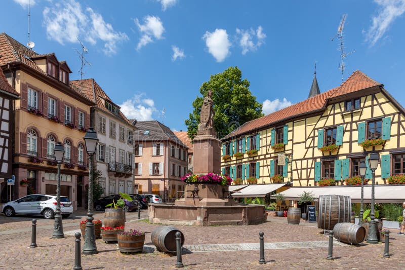 A picturesque colorful street of half-timber buildings with shops and cafes in the village of Ribeauville, in the Alsace region