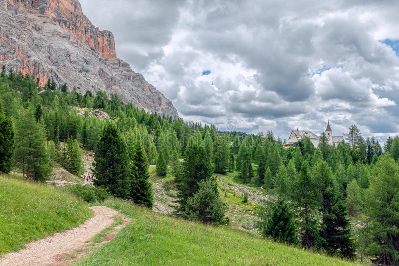 A picturesque path through an alpine meadow in the Italian Dolomites for hiking and cycling and alpine church