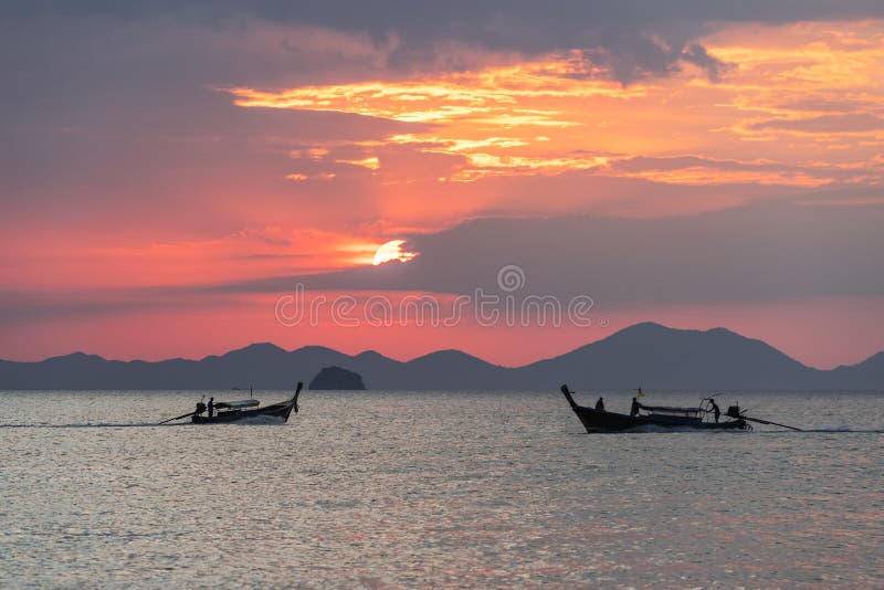 Seascape view with thai local long-tail boats floating in water at beautiful sunset on sea