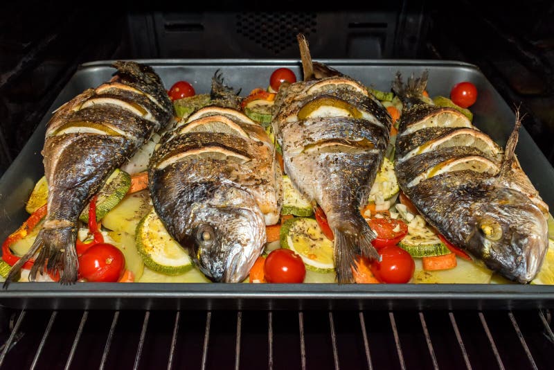 Piec dorada ryba z warzywami i cytryną w piekarniku obrazy stock Piec dorada ryba z warzywami i cytryną w piekarniku obrazy stock