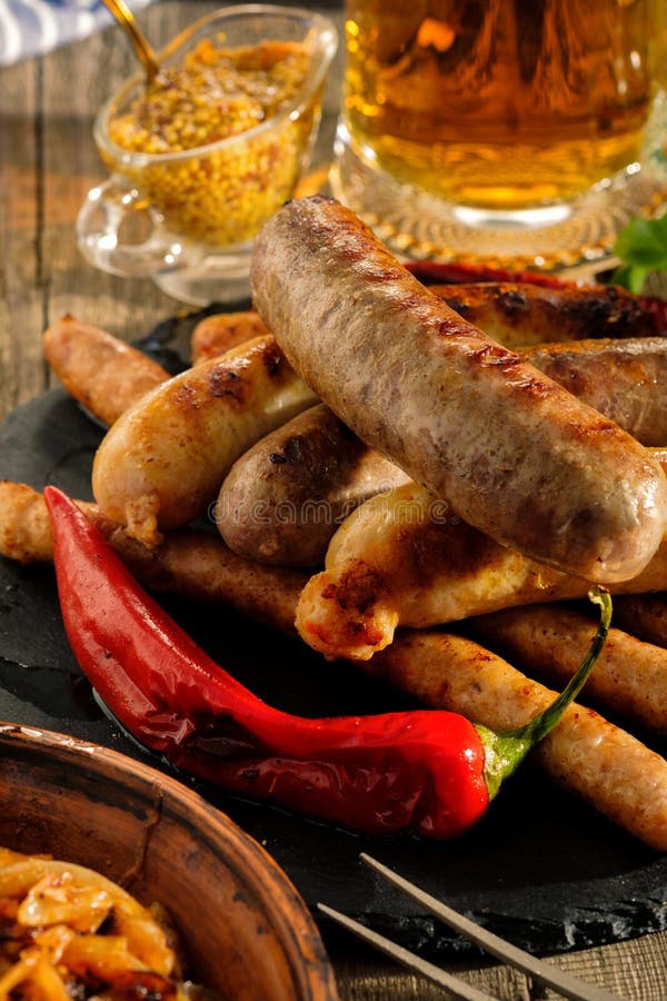 Piec na grillu kiełbasy i stewed kapusta z kubkiem piwo na drewnie zdjęcie royalty free Piec na grillu kiełbasy i stewed kapusta z kubkiem piwo na drewnie zdjęcie royalty free
