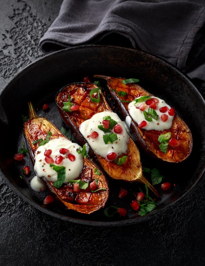Piec na grillu oberżyny z jogurtu kumberlandem, granatowów ziarnami, pietruszką i zieloną cebulą w obsadzie, odprasowywają roczni fotografia stock Piec na grillu oberżyny z jogurtu kumberlandem, granatowów ziarnami, pietruszką i zieloną cebulą w obsadzie, odprasowywają roczni fotografia stock