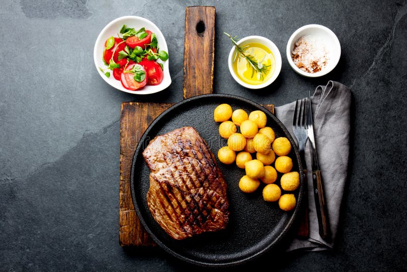 Piec na grillu wołowina stek słuzyć na obsady żelaza talerzu z pomidorowymi sałatki i grul piłkami Grill, bbq wołowiny mięsny ten obrazy royalty free Piec na grillu wołowina stek słuzyć na obsady żelaza talerzu z pomidorowymi sałatki i grul piłkami Grill, bbq wołowiny mięsny ten obrazy royalty free