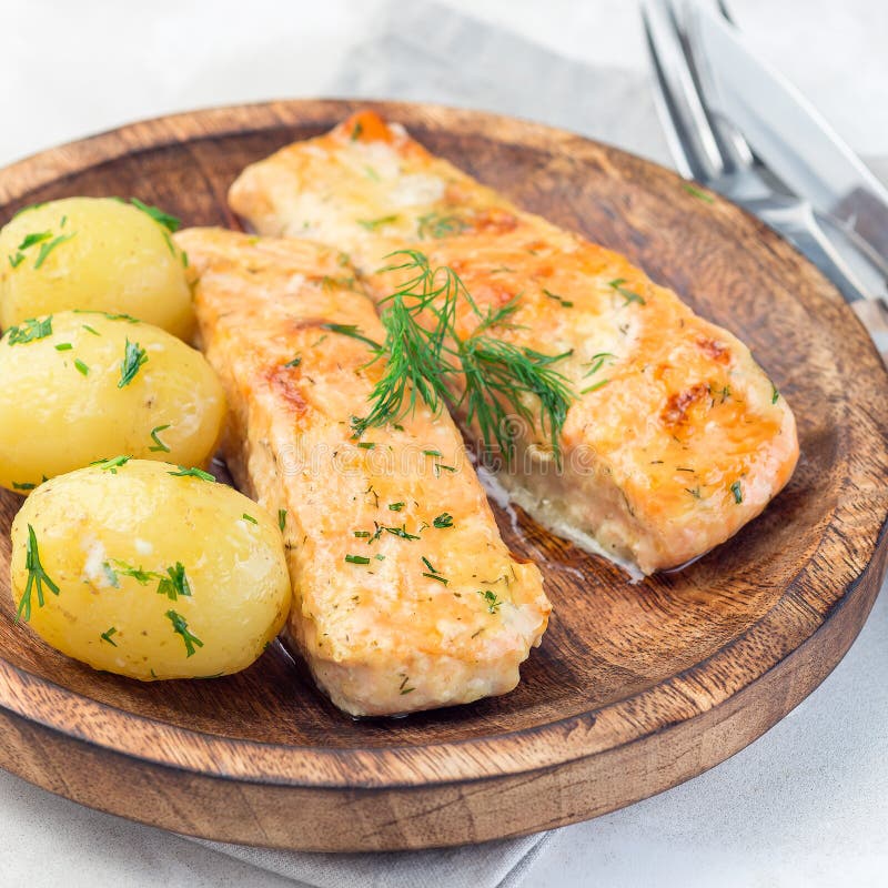 Piec łosoś w śmietankowym kumberlandzie z potomstwo gotującą się grulą nakrywającą z rozciekłym masłem i siekającym koperem na dr obrazy stock