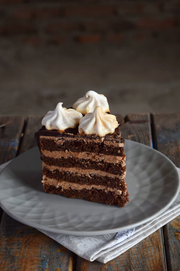 Piece of chocolate cake decorated with rosettes of meringue cream: chocolate-nut biscuit, caramel cream. Homemade baking stock images Piece of chocolate cake decorated with rosettes of meringue cream: chocolate-nut biscuit, caramel cream. Homemade baking stock images