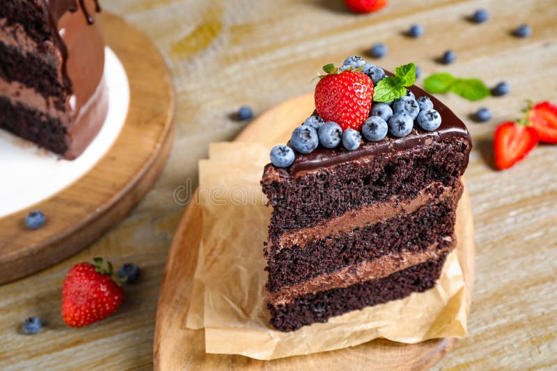 Piece of delicious chocolate cake decorated with berries on wooden table