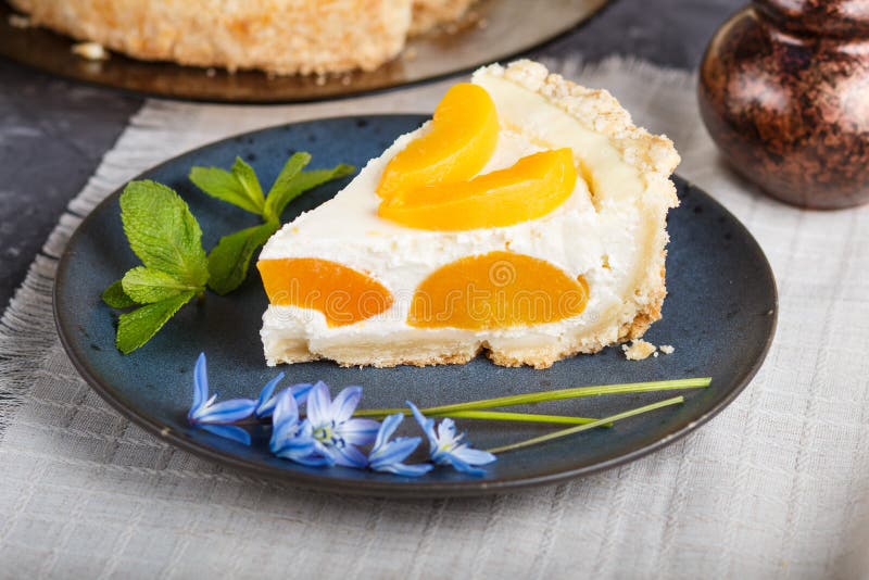 A piece of peach cheesecake on a blue ceramic plate with blue flowers and a cup of coffee on a black concrete background. side