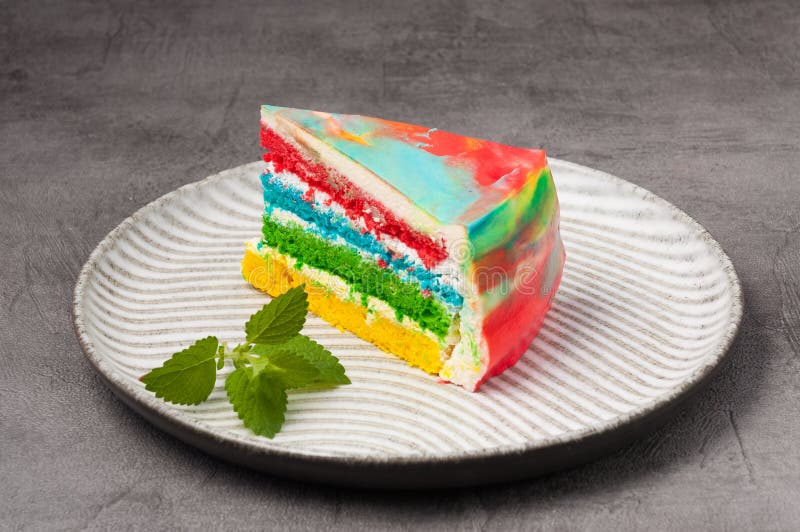 Piece of rainbow sponge cake with cream stock images