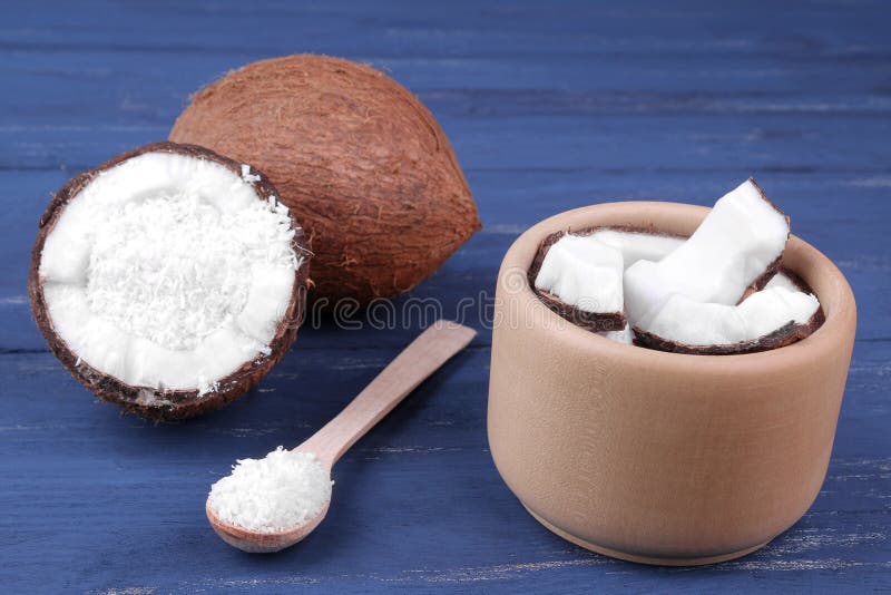 Pieces of coconut in a wooden bowl with a spoon with a whole coconut on a blue wooden background. stock image Pieces of coconut in a wooden bowl with a spoon with a whole coconut on a blue wooden background. stock image