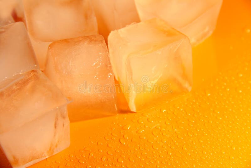 Pieces of ice on a bright background with water drops. Orange fresh background with ice flakes