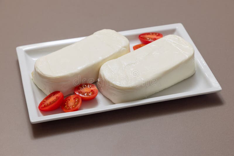 Pieces of Italian cow mozzarella cheese for pizza on a white rectangular plate