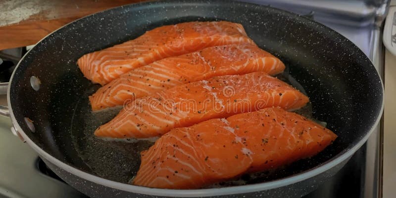 Pieces of red fish are fried in a frying pan royalty free stock image